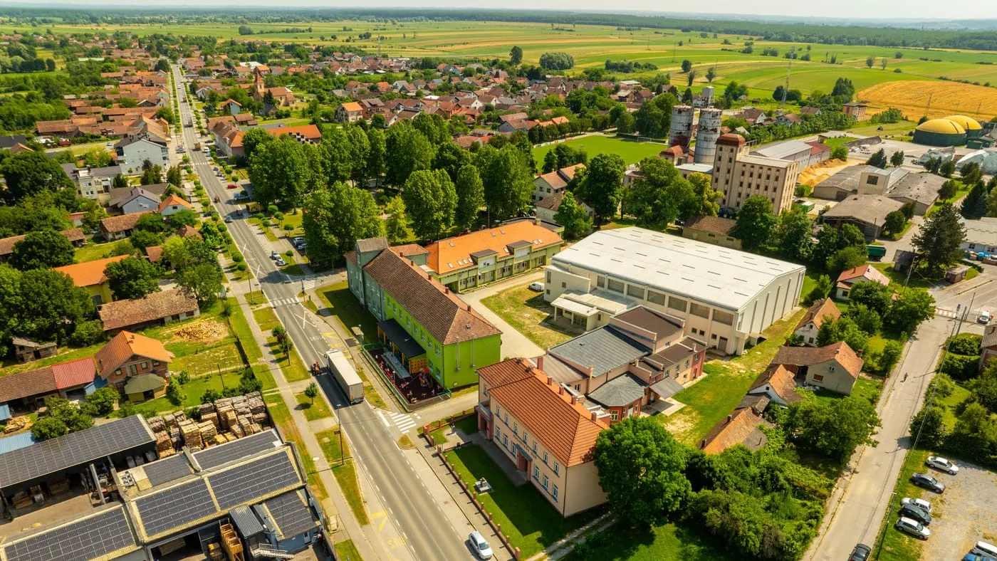 Flygbild över en småstad med genomfartsgata, låga hus i rader och åkrar bakom bebyggelsen.